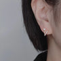 Gros plan sur l'oreille d'une femme mettant en valeur des boucles d'oreilles clips hypoallergéniques en zircon plaqué or 18 carats