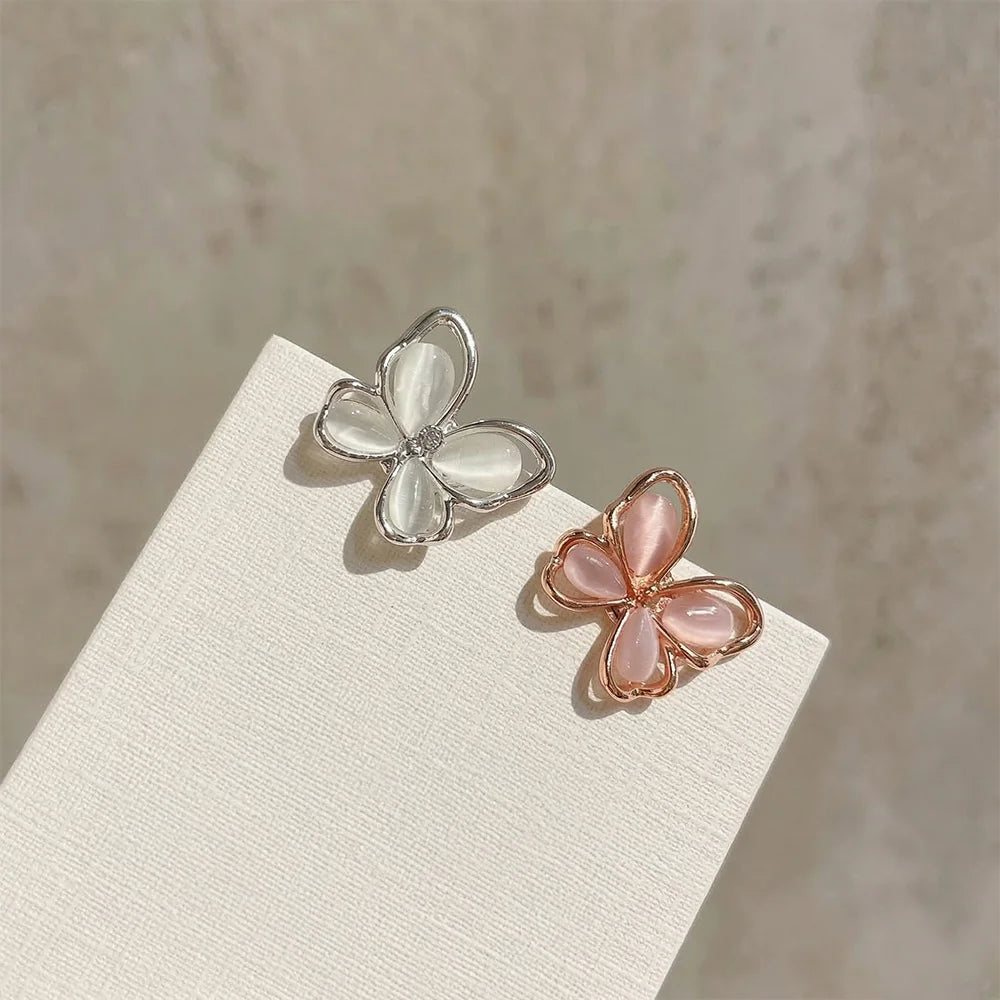 A comparison shot of the iridescent silver butterfly stud earring next to a rose gold version with pink-tinted iridescent wings.
