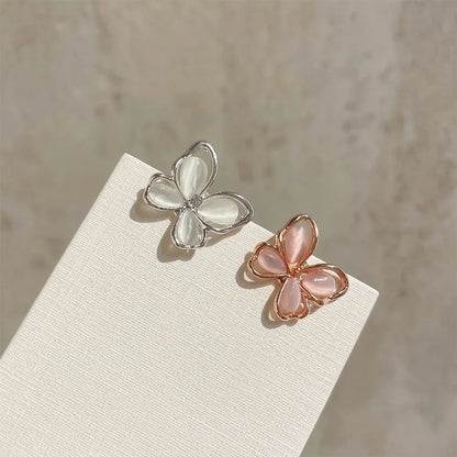 A comparison shot of the iridescent silver butterfly stud earring next to a rose gold version with pink-tinted iridescent wings.
