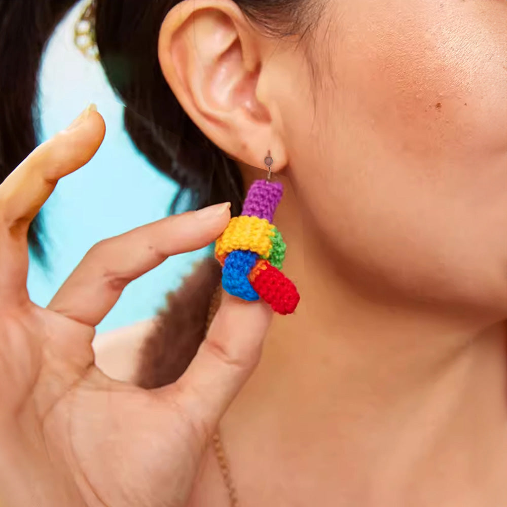 Woman wearing rainbow colored crochet dangle earrings, a unique gift to celebrate love or pride.