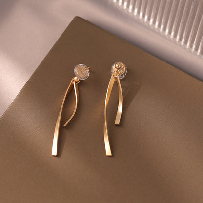 Dangle clip-on earrings feature a slender ribbon design for a touch of modern elegance. Made from gold-tone copper alloy with a secure coil clip closure, they're perfect for those with non-pierced ears.  Elevate your everyday look with these versatile earrings. 