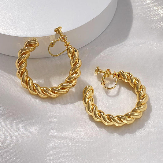 Chunky Gold Hoops with a Twist. These statement clip-on earrings in gold feature a unique twisted design for a touch of modern flair. Secure screw-back closure for comfort. Elevate your everyday look with a bold touch. 