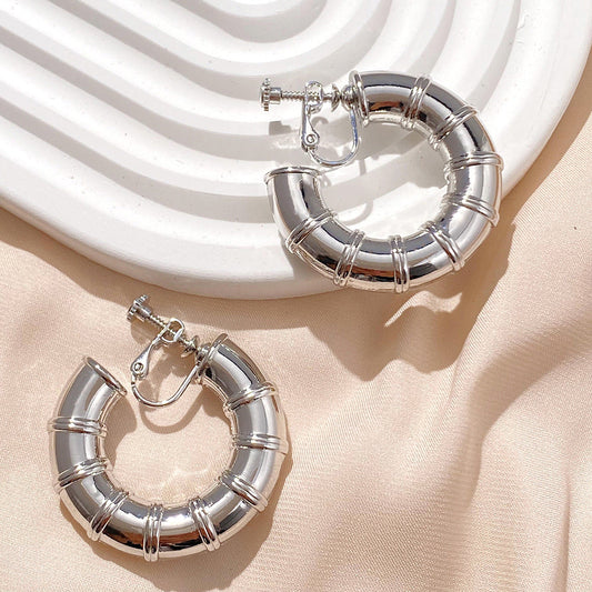 The Silver Bamboo Hoop Clip-On Earrings offer a classic, nature-inspired look with a secure screw-back closure. These iconic alloy earrings bring a touch of the natural world to your wardrobe.