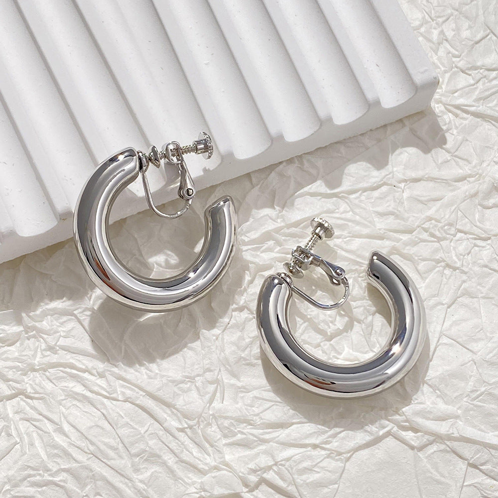 Boucles d'oreilles créoles classiques à clip en alliage d'argent vieilli, avec une finition brillante et une fermeture à vis, incarnant la force et l'amour-propre dans les tendances de la mode actuelles.