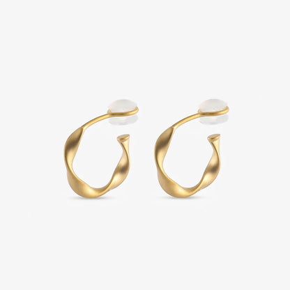 A pair of matte gold-toned organic abstract clip on hoop earrings shown from a frontal view.