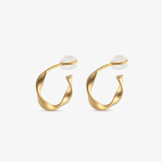 A pair of matte gold-toned organic abstract clip on hoop earrings shown from a frontal view.