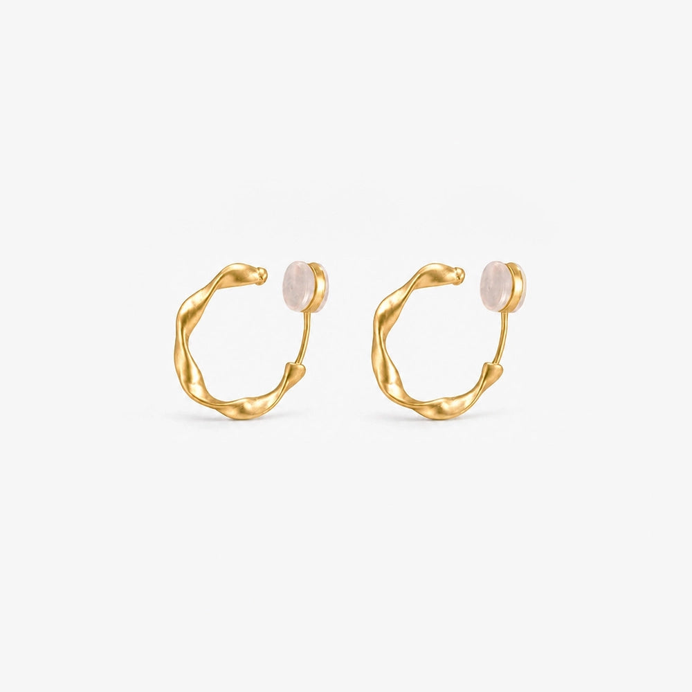 A pair of matte gold-toned organic abstract clip on hoop earrings shown from a frontal view.