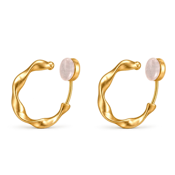 A pair of gold huggie hoop earrings with a smooth, organic wavy curve and a round pale pink stone set in each earring, shown on a plain white background.