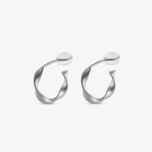 A pair of matte silver organic abstract clip-on hoop earrings with a soft satin finish.