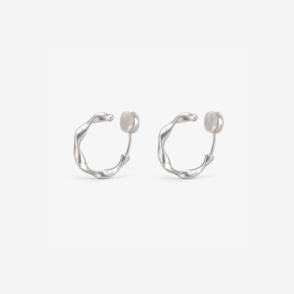 A pair of matte silver organic abstract clip-on hoop earrings with a soft satin finish.