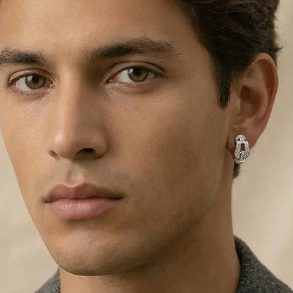 Close-up of a man wearing a diamond earring with a neutral background