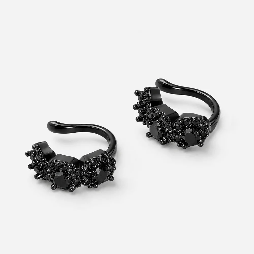 A pair of black metal huggie hoop earrings with cluster settings of black gemstones, photographed on a clean light gray background.