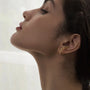 A model showcasing the elegant Aura gold zircon lobe cuff, demonstrating how it comfortably sits on the ear.