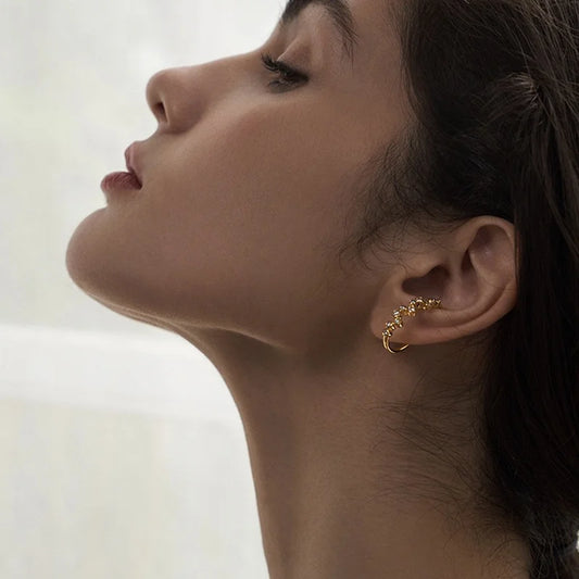A model showcasing the elegant Aura gold zircon lobe cuff, demonstrating how it comfortably sits on the ear.