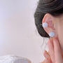 A model showcasing the curated ear stack with the white floral clip-on stud earring on her lobe and on her cartilage.