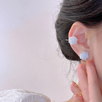 A model showcasing the curated ear stack with the white floral clip-on stud earring on her lobe and on her cartilage.