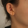 A model wearing the intricate floral filigree gold ear cuff on the lobe cartilage of her ear.