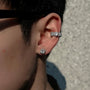A model wearing the Halo Nova silver triple zircon pavé clip-on ear cuff on the upper cartilage, paired with a matching stud, creating a stylish ear stack.