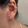 Gros plan sur un mannequin portant une manchette d'oreille en argent sterling cloutée sur son cartilage conque pour un look d'accumulation d'oreilles minimaliste et tendance.
