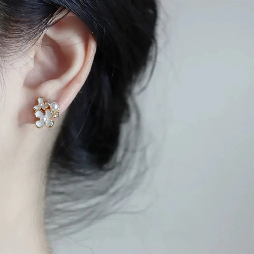A close-up of a model's ear wearing a White Blossom Pearl invisible clip-on earring, demonstrating its delicate floral design and comfortable fit on the earlobe.
