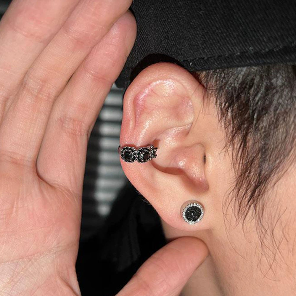 A model wearing the "Midnight Star" black triple zircon pavé clip-on ear cuff on the upper cartilage, paired with a matching black stud, showcasing an edgy ear stack.