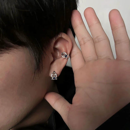 A model wearing the Neptune silver trident clip-on ear cuff on the upper helix, paired with a matching stud on the lobe, showcasing a stylish ear stack.