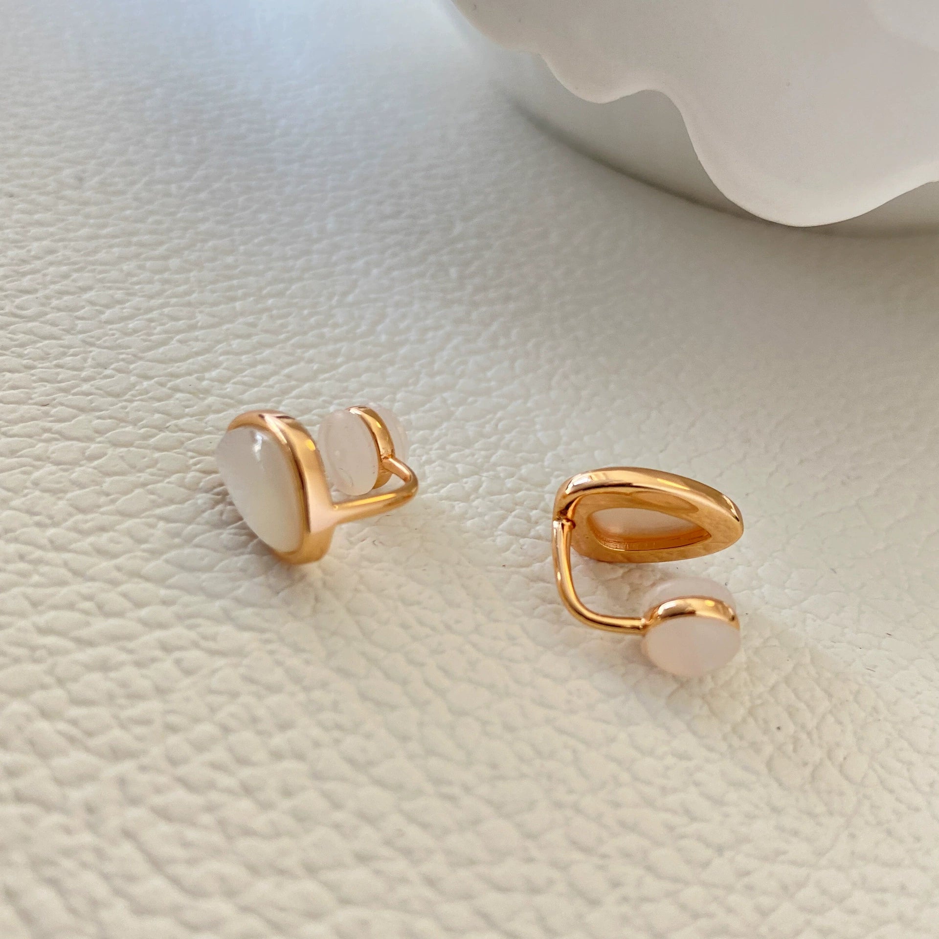 Gros plan sur l'arrière d'une boucle d'oreille à clip en nacre en forme de larme, mettant en valeur l'anneau en métal or rose et le coussinet de fermeture sphérique confortable sans perçage.