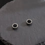 A pair of Nightfall Pavé black crystal magnetic stud earrings, showcasing their sparkling design on a dark slate surface.