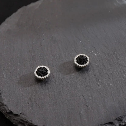 A pair of Nightfall Pavé black crystal magnetic stud earrings, showcasing their sparkling design on a dark slate surface.