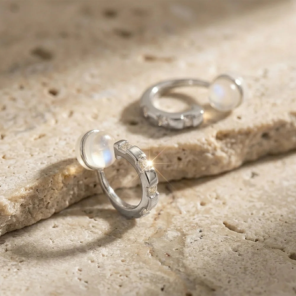 Close-up of 16k white gold plated baguette CZ earrings on a stone surface, showing the comfort c-type clip-on.