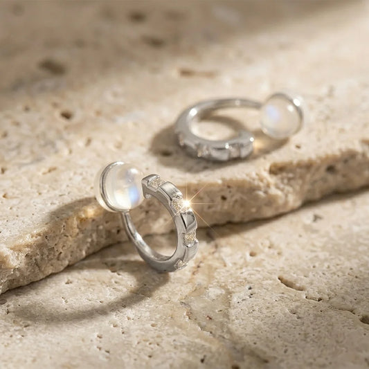 Close-up of 16k white gold plated baguette CZ earrings on a stone surface, showing the comfort c-type clip-on.