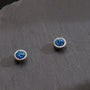 A pair of Nova Iridescent Blue Galaxy Magnetic Stud Earrings, showcasing their sparkling blue druzy texture on a dark slate background.