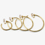 Thin gold hoop clip-on earrings in a range of sizes lined up from smallest to largest