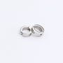A pair of silver spring-loaded clip-on hoop earrings with a subtle zircon accent, styled together on a clean white background.