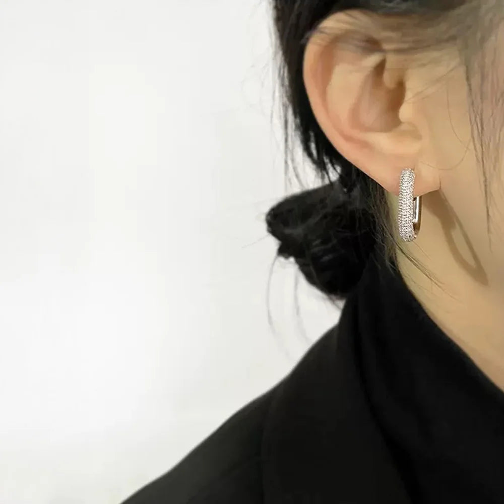 A side profile view of a model wearing the silver pave square-edge clip-on hoop earrings, highlighting their elegant fit on the earlobe.
