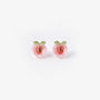 A pair of translucent pink resin peach magnetic stud earrings with green leaf details and a realistic pit center, isolated on a white background.