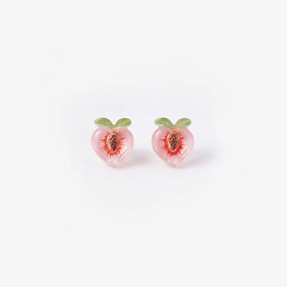 A pair of translucent pink resin peach magnetic stud earrings with green leaf details and a realistic pit center, isolated on a white background.