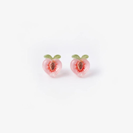 A pair of translucent pink resin peach magnetic stud earrings with green leaf details and a realistic pit center, isolated on a white background.