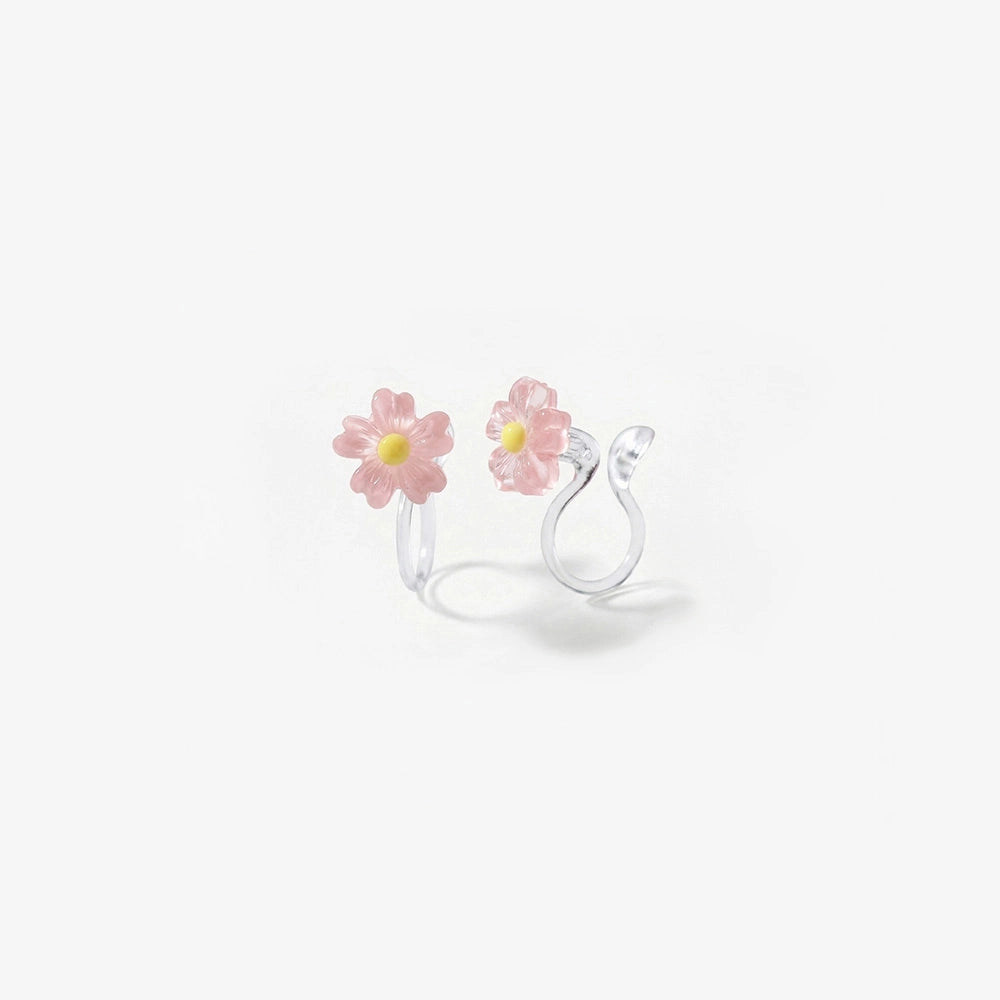 A pair of pink daisy flower earrings with a candy color translucent finish and stud clip-on backs.