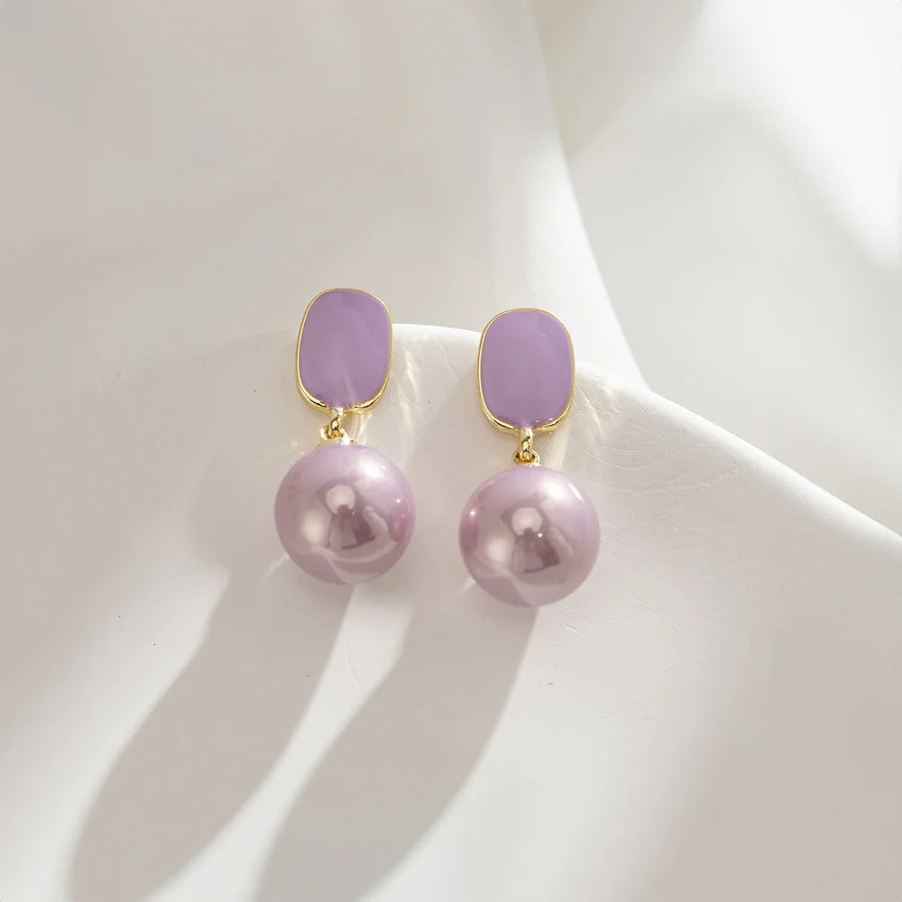 Close-up of the Purple Pearl Clip-On Drop Earrings showcasing 20mm faux purple pearls with pink enamel accents.