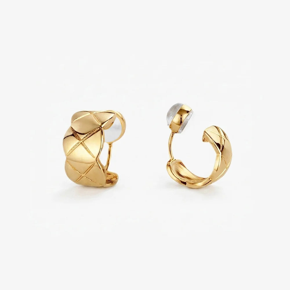 A pair of gold-toned quilted huggie clip on earrings featuring a lattice etched pattern.