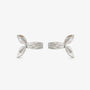 Une paire de boucles d'oreilles à clip sculpturales et rayonnantes, plaquées argent, conçues pour ressembler à une manchette d'oreille en forme de nœud de ruban épais, isolées sur un fond blanc.