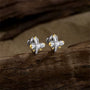 Regal two-tone cross clip-on earrings with gold accents and a CZ center stone, displayed on a dark wooden background.