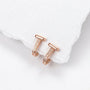 A pair of rose gold huggie hoop earrings with pavé-set clear stones, displayed on a textured white paper towel corner against a white background.
