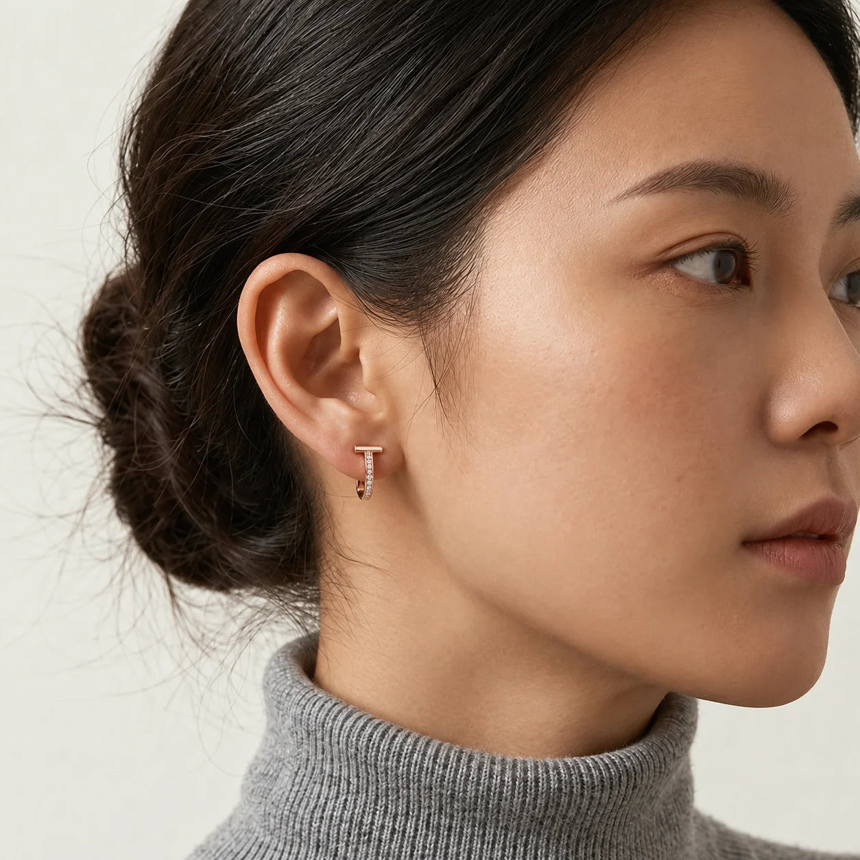 A stylish woman wearing the rose gold T-motif clip-on earrings, showcasing the elegant fit and designer inspired jewelry look.