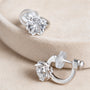 Close-up of the petal facets on clear sakura CZ clip-on studs resting on a beige display