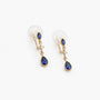 A pair of gold-toned dangle earrings with marquise-cut blue gemstones and teardrop-shaped blue gemstones, shown on a plain white background.