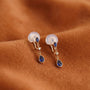 Pair of earrings with blue gemstones on a brown fabric background