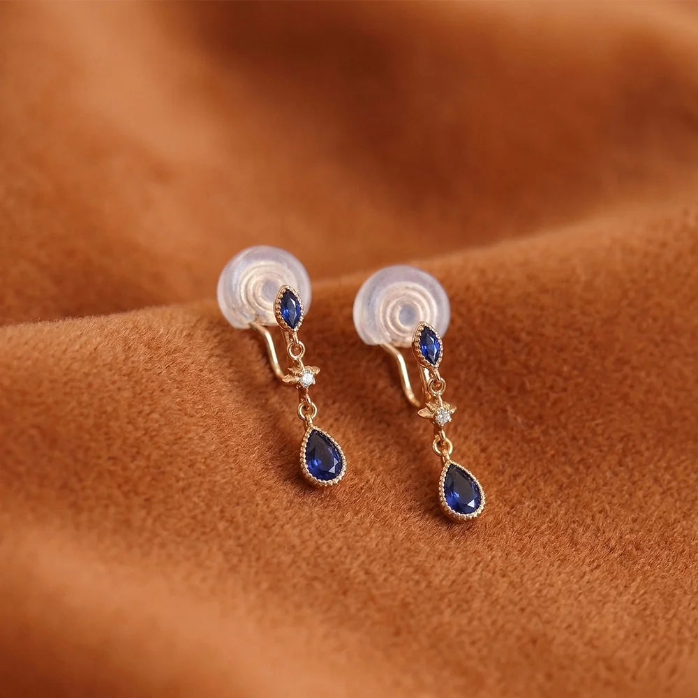 Pair of earrings with blue gemstones on a brown fabric background