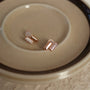 Rose gold clip on earrings with shining stones on a beige plate